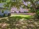 A spacious backyard with green grass offers a serene outdoor space, shaded by mature trees at 824 Garfish Ave, New Smyrna Beach, FL 32169