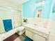 Bathroom boasts an enclosed shower with glass doors, bright blue accent wall, and ample vanity storage at 824 Garfish Ave, New Smyrna Beach, FL 32169