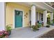 Bright teal front door and gray porch with potted plants at 915 Maple St, New Smyrna Beach, FL 32169