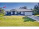 Single-story home with metal roof, attached garage, and landscaping at 977 Bay Dr, New Smyrna Beach, FL 32168