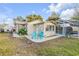 Backyard featuring a patio area with two blue chairs, lush landscaping, and an enclosed pool area at 1052 Tompkins Dr, Port Orange, FL 32129