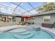 A backyard featuring a refreshing in-ground pool, hot tub and seating area under a screened enclosure at 1052 Tompkins Dr, Port Orange, FL 32129