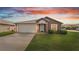 House exterior view at dusk, featuring a two-car garage and well-manicured lawn at 230 Oak Branch Dr, Edgewater, FL 32141