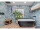 Modern bathroom featuring a black freestanding tub, blue tile accent wall, and pebble tile flooring at 4946 Halifax Dr, Port Orange, FL 32127