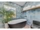 Modern bathroom featuring a black freestanding tub, blue tile accent wall, and pebble tile flooring at 4946 Halifax Dr, Port Orange, FL 32127