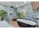 Modern bathroom featuring a black freestanding tub, blue tile accent wall, and pebble tile flooring at 4946 Halifax Dr, Port Orange, FL 32127