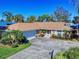 One-story home with brown roof, driveway, and palm trees at 103 Sea St, New Smyrna Beach, FL 32168