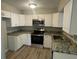 Modern kitchen featuring stainless steel appliances, granite countertops, and ample white cabinetry at 1500 Wildrose Ln, Daytona Beach, FL 32117