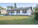 White brick ranch house with gray roof, and a green lawn at 18 Wildwood Dr, Edgewater, FL 32132