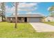 Front view of a single-story house with a gray garage door and a well-maintained lawn at 1820 Sabal Palm Dr, Edgewater, FL 32132