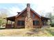 Log cabin exterior with stone fireplace and wrap-around porch at 187 N Samsula Dr, New Smyrna Beach, FL 32168