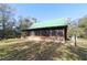 Log cabin with screened porch, green metal roof, and surrounding trees at 187 N Samsula Dr, New Smyrna Beach, FL 32168