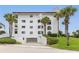 White building exterior with palm trees and a garage at 3001 S Atlantic Ave # 503, New Smyrna Beach, FL 32169