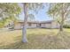 Tan house with a large front yard and mature trees at 3103 Royal Palm Dr, Edgewater, FL 32141