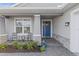 Front porch with blue door, stone accents, and small seating area at 3309 Modena Way, New Smyrna Beach, FL 32168