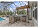 Outdoor kitchen with built-in grill, refrigerator, and stone countertops at 3309 Modena Way, New Smyrna Beach, FL 32168