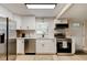 Modern kitchen with stainless steel appliances, white cabinets, and black hardware, complemented by white tile backsplash at 388 N Glencoe Rd, New Smyrna Beach, FL 32168