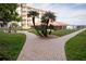 Brick-paved pathways wind through a lush courtyard, showcasing palm trees and a building exterior at 4155 S Atlantic Ave # 111, New Smyrna Beach, FL 32169