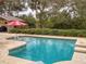 Inviting swimming pool with a red umbrella and surrounding landscaping at 4514 Saxon Dr, New Smyrna Beach, FL 32169