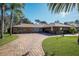 Brick ranch house with paver driveway, mature landscaping, and American flag at 803 Silk Oak Ct, New Smyrna Beach, FL 32168