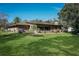 Back of house with large windows, patio, and grassy yard at 803 Silk Oak Ct, New Smyrna Beach, FL 32168