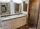 Bathroom featuring a dual sink vanity with stone countertop, wood-look tile shower, and decorative mirrors at 1202 12Th St, Edgewater, FL 32132