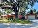 Home exterior showcasing lush landscaping, mature trees, and a detached garage at 1202 12Th St, Edgewater, FL 32132