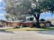 Exterior view of the single story home with a detached garage and mature trees at 1202 12Th St, Edgewater, FL 32132