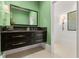 Modern bathroom with dark vanity, green walls, and floating sink at 1309 Hill St, New Smyrna Beach, FL 32169