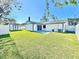 Expansive backyard with a storage shed, blue patio, green grass, and a white fence, offering ample outdoor space at 2101 Oriole Ln, South Daytona, FL 32119