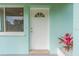 White front door with a semicircular window and a red plant beside it at 211 Maurice Ave, New Smyrna Beach, FL 32168