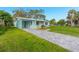 Light teal single story house with a paved driveway and landscaping at 211 Maurice Ave, New Smyrna Beach, FL 32168