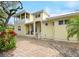 Two-story yellow house with a white porch, and a brick driveway at 221 Columbus Ave, New Smyrna Beach, FL 32169