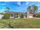 Gray house with red door, stone chimney and attached garage. Lush lawn at 2507 Milton Ave, New Smyrna Beach, FL 32168