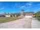 Gray house with red door, stone chimney, and attached garage. Long driveway at 2507 Milton Ave, New Smyrna Beach, FL 32168