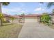 Front view of a tan house with a large garage and well-maintained landscaping at 28 Lake Fairgreen Cir, New Smyrna Beach, FL 32168