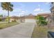 Front view of a tan house with a large garage and mature palm trees at 28 Lake Fairgreen Cir, New Smyrna Beach, FL 32168