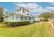 A teal house with a metal roof, lush landscaping, and a spacious front yard at 2817 Bay Side Dr, New Smyrna Beach, FL 32168