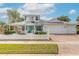 Two-story light teal home with a large driveway, white picket fence, and mature landscaping at 2817 Bay Side Dr, New Smyrna Beach, FL 32168