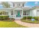 Charming house exterior featuring a teal facade, white porch, and lush landscaping at 2817 Bay Side Dr, New Smyrna Beach, FL 32168