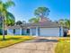 Light blue single story house with attached garage and palm trees at 3220 Tamarind Dr, Edgewater, FL 32141