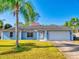 Single story house with a light blue exterior, attached garage, and palm trees at 3220 Tamarind Dr, Edgewater, FL 32141