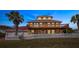 Two-story house with red metal roof, white fence, and palm trees at 3726 S Atlantic Ave, New Smyrna Beach, FL 32169