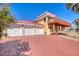 Three-car garage with red brick driveway and tropical landscaping at 3726 S Atlantic Ave, New Smyrna Beach, FL 32169