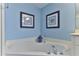 Bright bathroom featuring a soaking tub, blue walls, and beach-themed decor for a relaxing ambiance at 432 Bouchelle Dr # 403, New Smyrna Beach, FL 32169