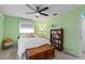 Light green bedroom with a queen bed, built-in shelving, and ceiling fan at 705 Wayne Ave, New Smyrna Beach, FL 32168