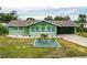 Charming light green house with a well-maintained lawn and dark garage door at 705 Wayne Ave, New Smyrna Beach, FL 32168