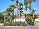Entrance to Venetian Villas featuring lush landscaping and palm trees, offering a serene and welcoming atmosphere at 113 Lagoon Ct, New Smyrna Beach, FL 32169