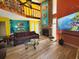 Bright, multi-story living room featuring a fireplace, vibrant accent walls, wood floors, and a cozy loft space at 113 Lagoon Ct, New Smyrna Beach, FL 32169