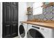 Laundry room with wooden countertops, washer, dryer, and black and white tile at 1409 Arbitus Cir, Oviedo, FL 32765